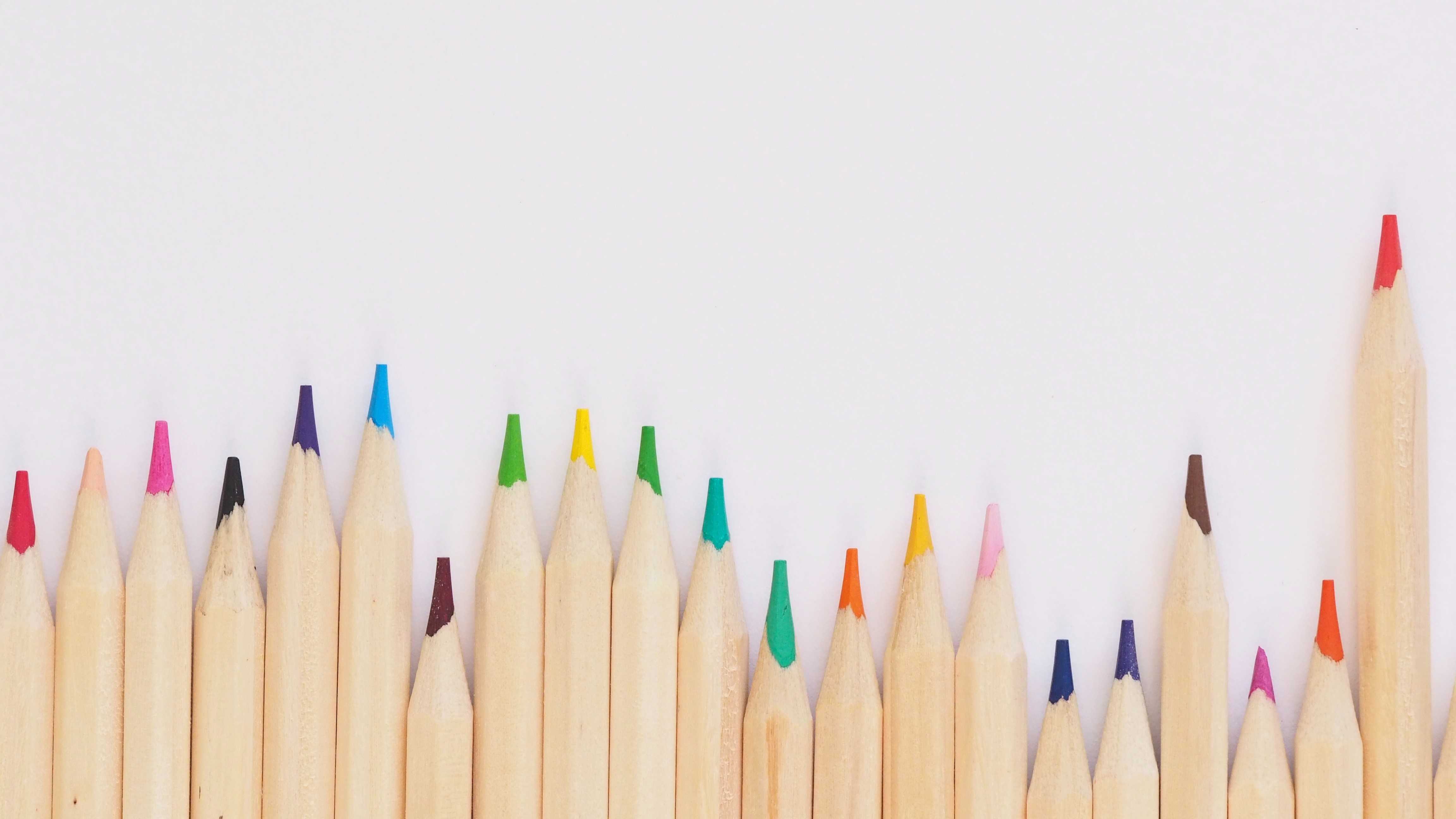 Colored pencil lined up on top of white surface